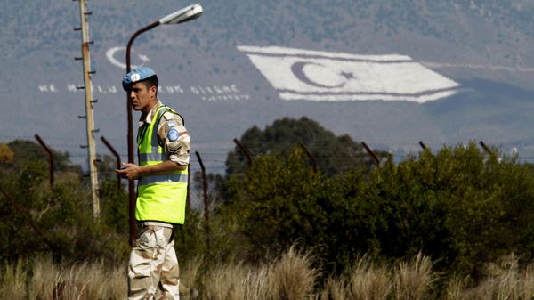An Argentinean UN peacekeeper stands guard in front of the painted Turkish flag, left, and the Turkish Cypriot flag on Pentadaktilos mountain in northern Cyprus - Sputnik International