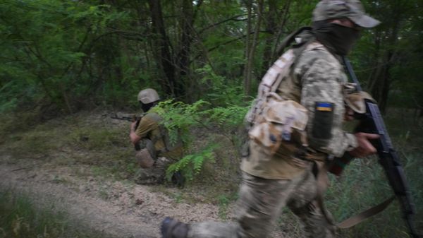A Ukrainian soldier runs while another covers his back on June 14, 2022. - Sputnik International