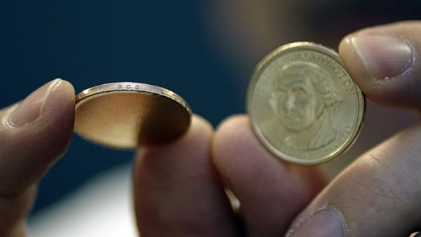 One of a group of the misstruck new presidential dollar coins, left, that has the In God We Trust lettering stamped on the edge, but showing no presidential face, is displayed next to a new presidential dollar showing President George Washington, right, at the Professional Coin Grading Service offices in Santa Ana, Calif., Tuesday, March 13, 2007. - Sputnik International