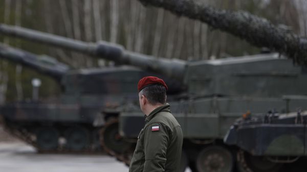 A Polish soldier walks next to the Leopard 2 tanks during a training at a military base and test range in Swietoszow, Poland, Monday, Feb. 13, 2023 - Sputnik International