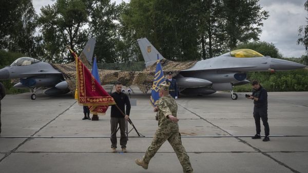 Volodymyr Zelenskyy hands over the flag of a military unit on the occasion of the Air Forces Day against the background of Ukraine's Air Force's F-16 fighter jets in an undisclosed location in Ukraine, Sunday, Aug. 4, 2024.  - Sputnik International