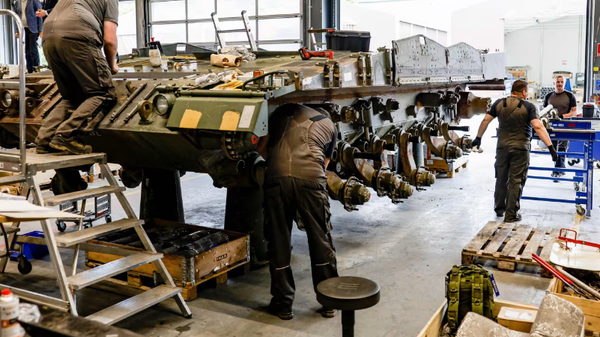 Screenshot showing technicians working on a vehicle at a Rheinmetall facility in Germany. - Sputnik International