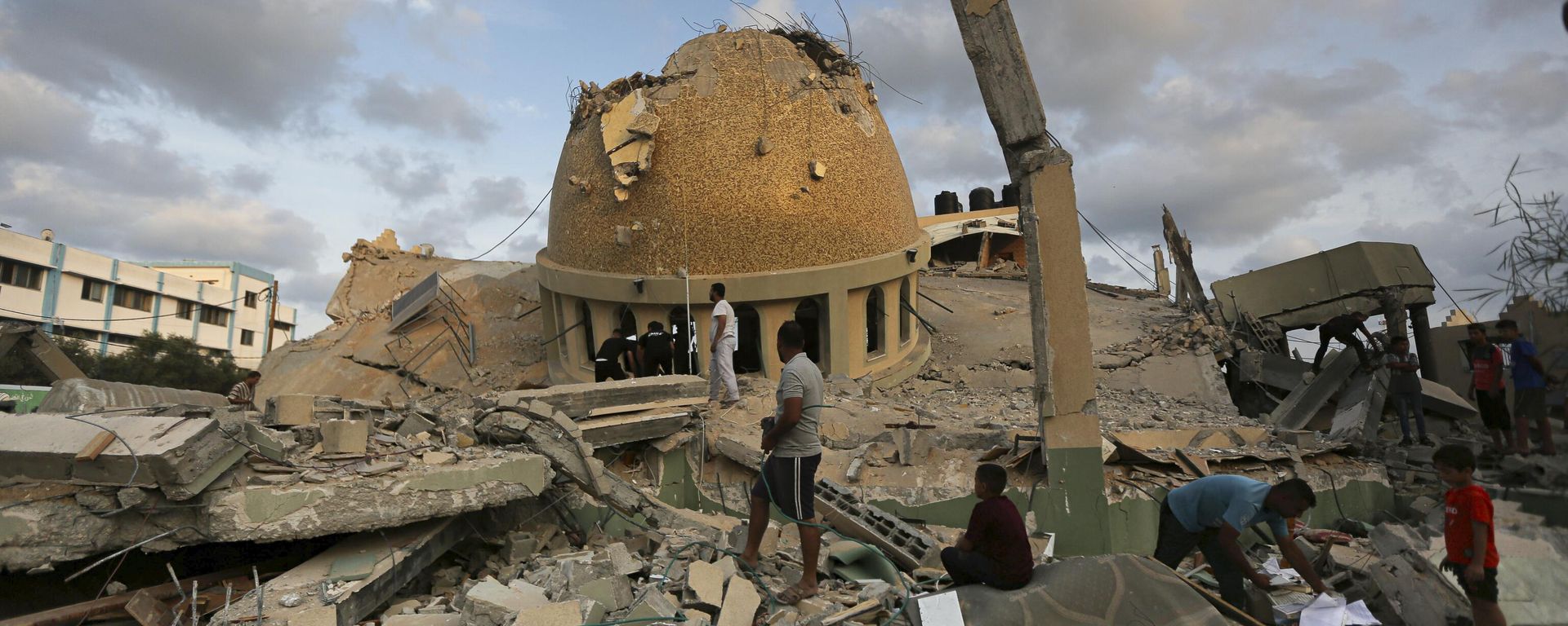 People stand outside a mosque destroyed in an Israeli air strike in Khan Younis, Gaza Strip, Sunday, Oct.8, 2023. People stand outside a mosque destroyed in an Israeli air strike in Khan Younis, Gaza Strip, Sunday, Oct.8, 2023. - Sputnik International, 1920, 09.10.2024