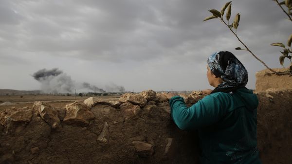 A Kurdish woman, standing in Mursitpinar, on the outskirts of Suruc, on the Turkey-Syria border, watches smoke from fires caused by strikes - Sputnik International