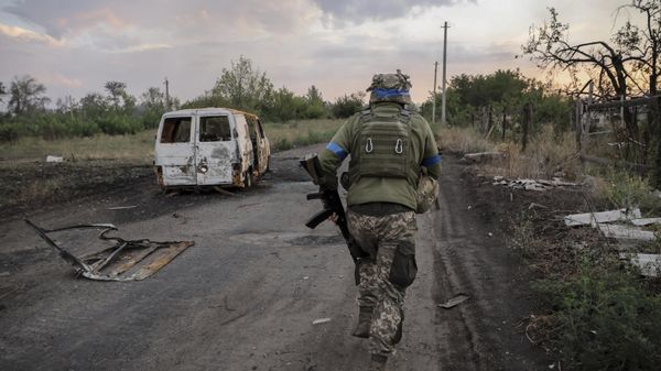 A serviceman of the 24th Mechanised Brigade runs past a damaged car at the frontline in Donetsk region.   - Sputnik International
