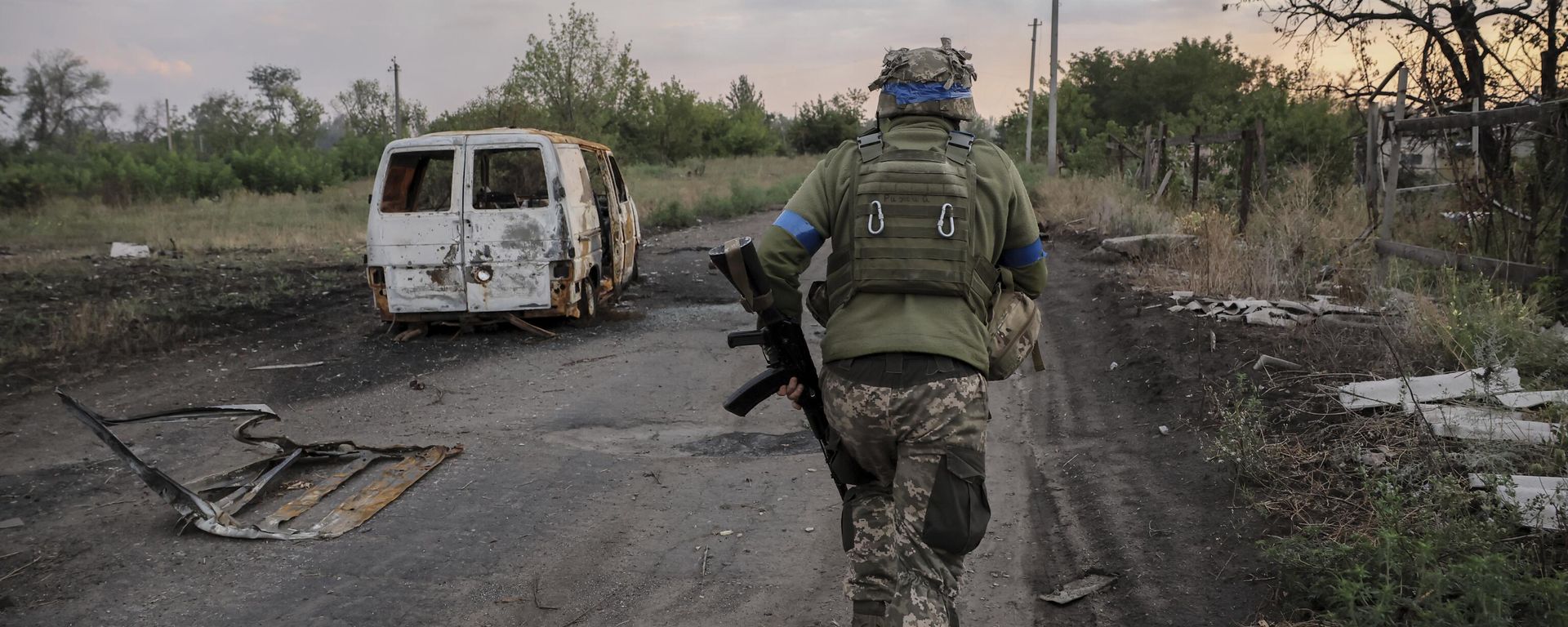 A serviceman of the 24th Mechanised Brigade runs past a damaged car at the frontline in Donetsk region.   - Sputnik International, 1920, 16.02.2026