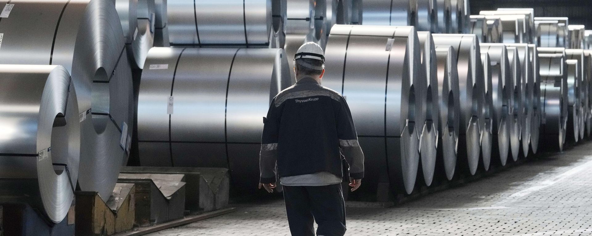 A steel worker walks beside steel coils during a visit of EU Commissioner for Prosperity and Industrial Strategy Stephane Sejourne at the Thyssenkrupp steelworks in Duisburg, Germany, on March 20, 2025.  - Sputnik International, 1920, 12.11.2025