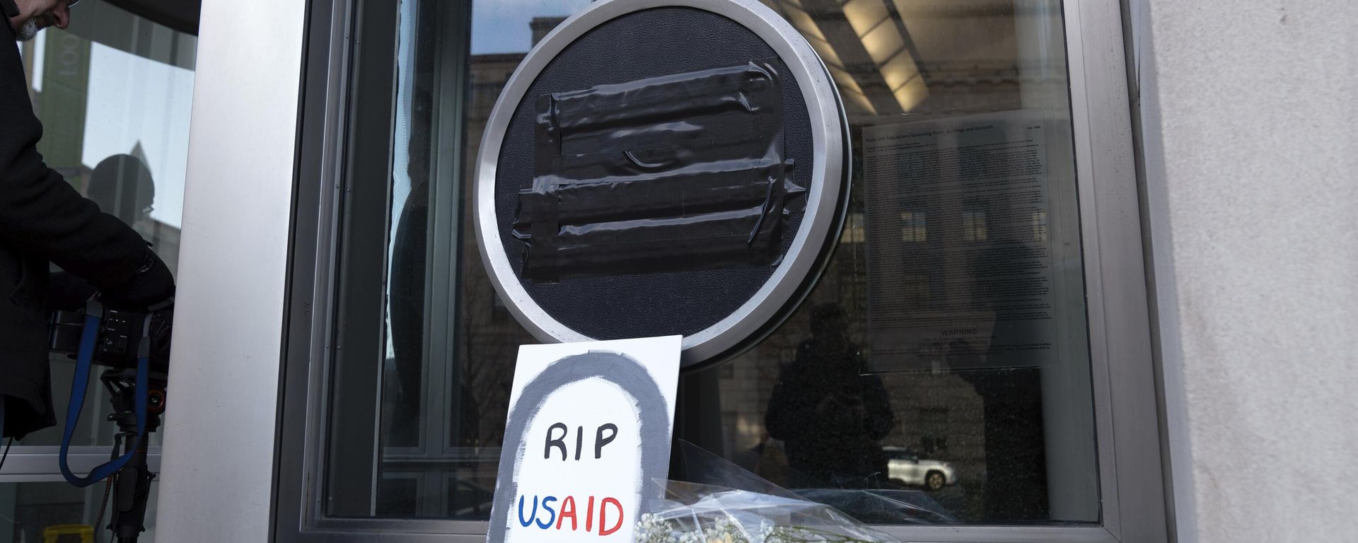 Flowers and a sign are placed outside the headquarters of the U.S. Agency for International Development, or USAID, Friday, Feb. 7, 2025, in Washington.  - Sputnik International, 1920, 09.04.2025