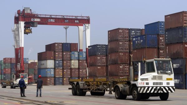 Workers watch as a truck passes by stacks of shipping containers at a port in Yingkou in northeastern China's Liaoning Province.  - Sputnik International