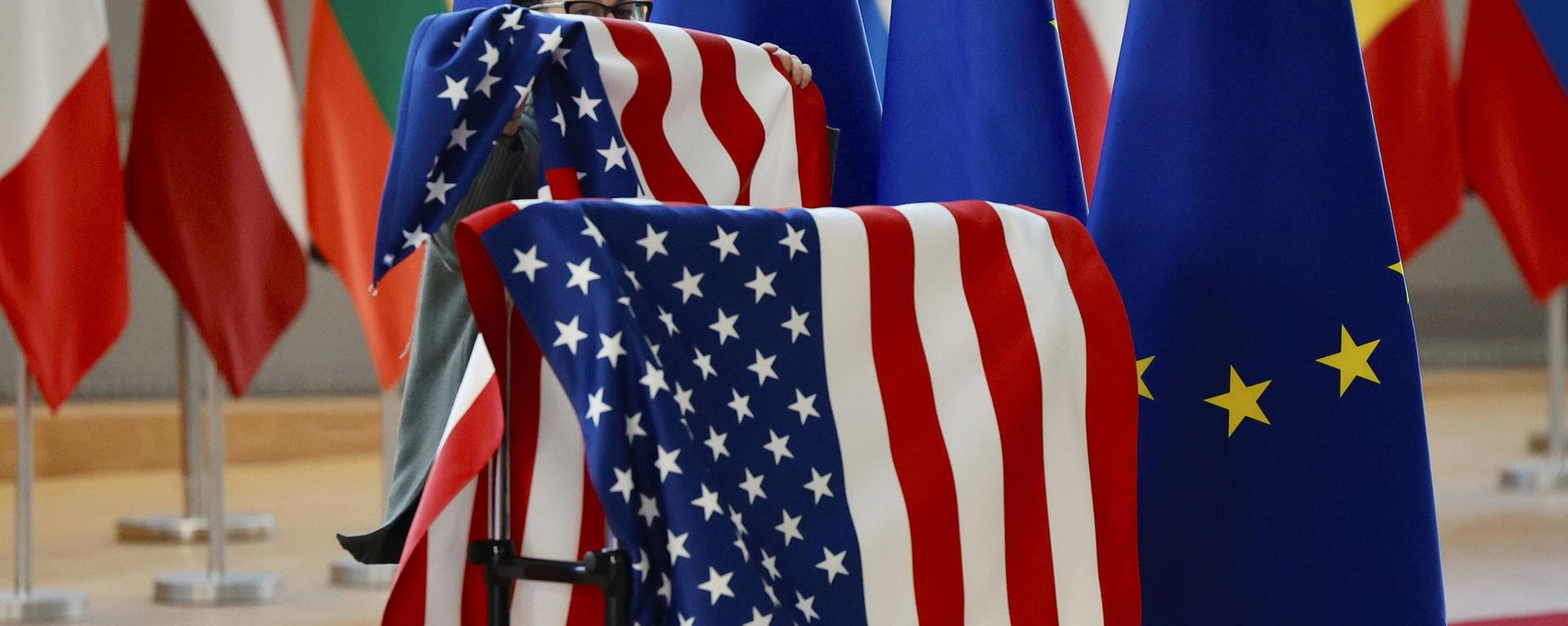 A member of protocol adjusts the U.S. and EU flags prior to the arrival of US Secretary of State Antony Blinken and European Council President Charles Michel during an extraordinary EU foreign ministers meeting at the European Council building in Brussels, Friday, March 4, 2022 - Sputnik International, 1920, 24.04.2025