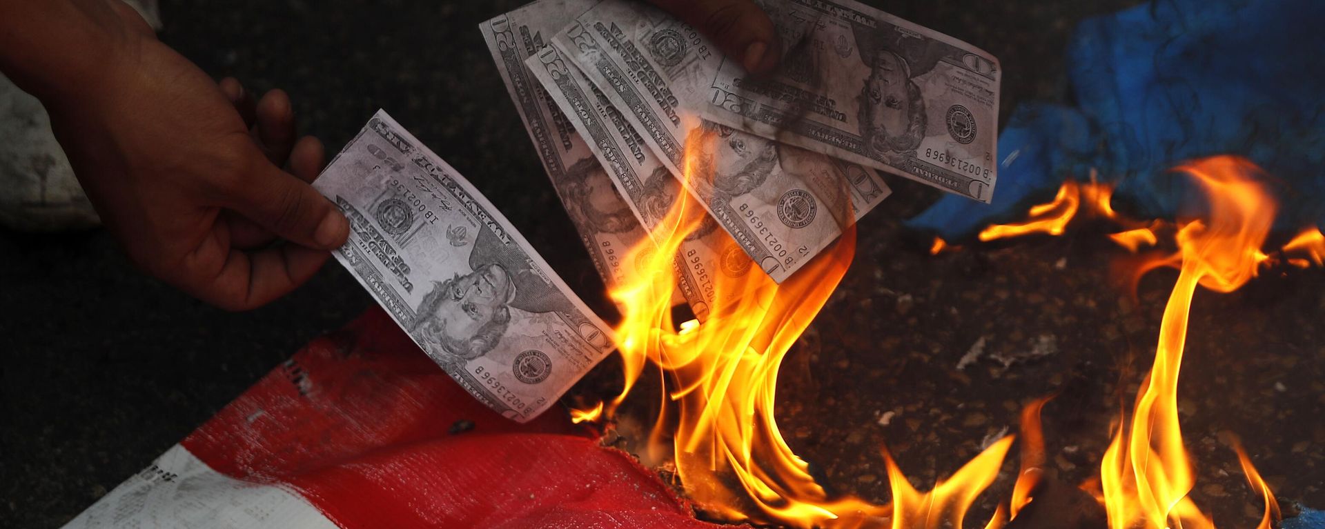 A supporter of a communist group burns representation of U.S. currency, during a protest against U.S. interference in Lebanon's affairs, near the U.S. embassy, in Aukar northeast of Beirut, Lebanon, Friday, July 10, 2020 - Sputnik International, 1920, 29.06.2025