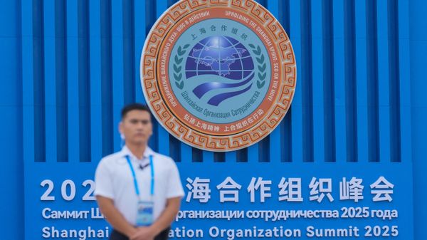A security guard stands near the logo of Shanghai Cooperation Organization (SCO) member states outside the venue in Tianjin, China , Saturday, Aug. 30, 2025. - Sputnik International