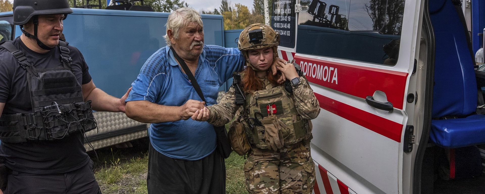 Police officers help Mykola Puzyk, 70, who lost his wife Tetiana Puzyk, 68, to move from an armored car to a ambulance from the village of Yarova. September 9, 2025. - Sputnik International, 1920, 09.09.2025