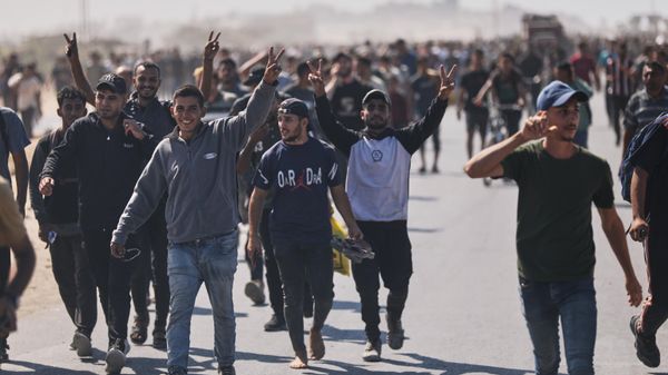 Displaced Palestinians wave to the camera as they walk along the coastal road in the direction of Gaza City, in the northern Gaza Strip, Friday, Oct. 10, 2025, after Israel and Hamas have agreed to a pause in their war and the release of the remaining hostages. - Sputnik International