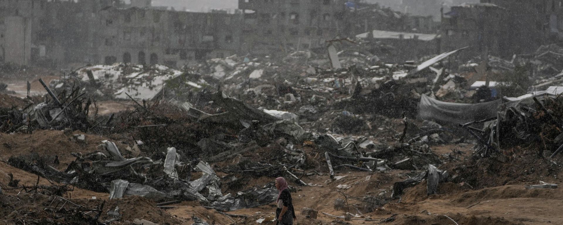 A Palestinian woman walks through a rainstorm past buildings destroyed in Israeli strikes in the Sheikh Radwan neighborhood of Gaza City, Friday, Nov. 14, 2025. A Palestinian woman walks through a rainstorm past buildings destroyed in Israeli strikes in the Sheikh Radwan neighborhood of Gaza City, Friday, Nov. 14, 2025. - Sputnik International, 1920, 15.11.2025