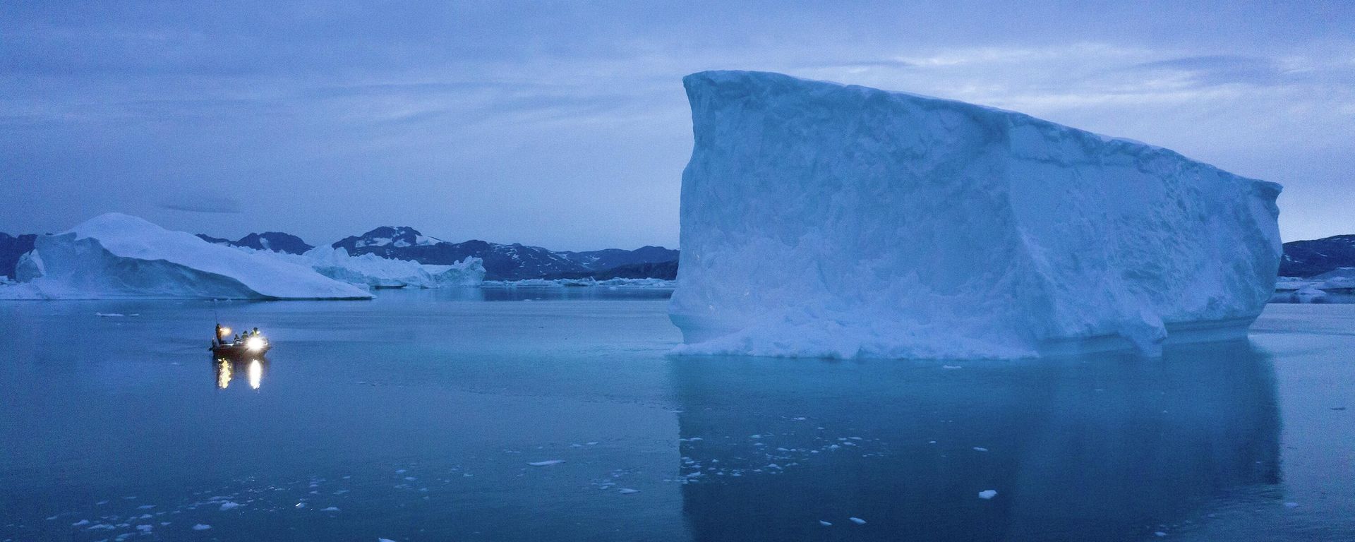 In this Aug. 15, 2019, photo, a boat navigates at night next to icebergs in eastern Greenland.   - Sputnik International, 1920, 12.01.2026