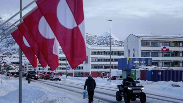 A man rides by on a quad bike past a row of Greenlandic national flags in Nuuk, Greenland, Wednesday, Jan. 14, 2026. - Sputnik International