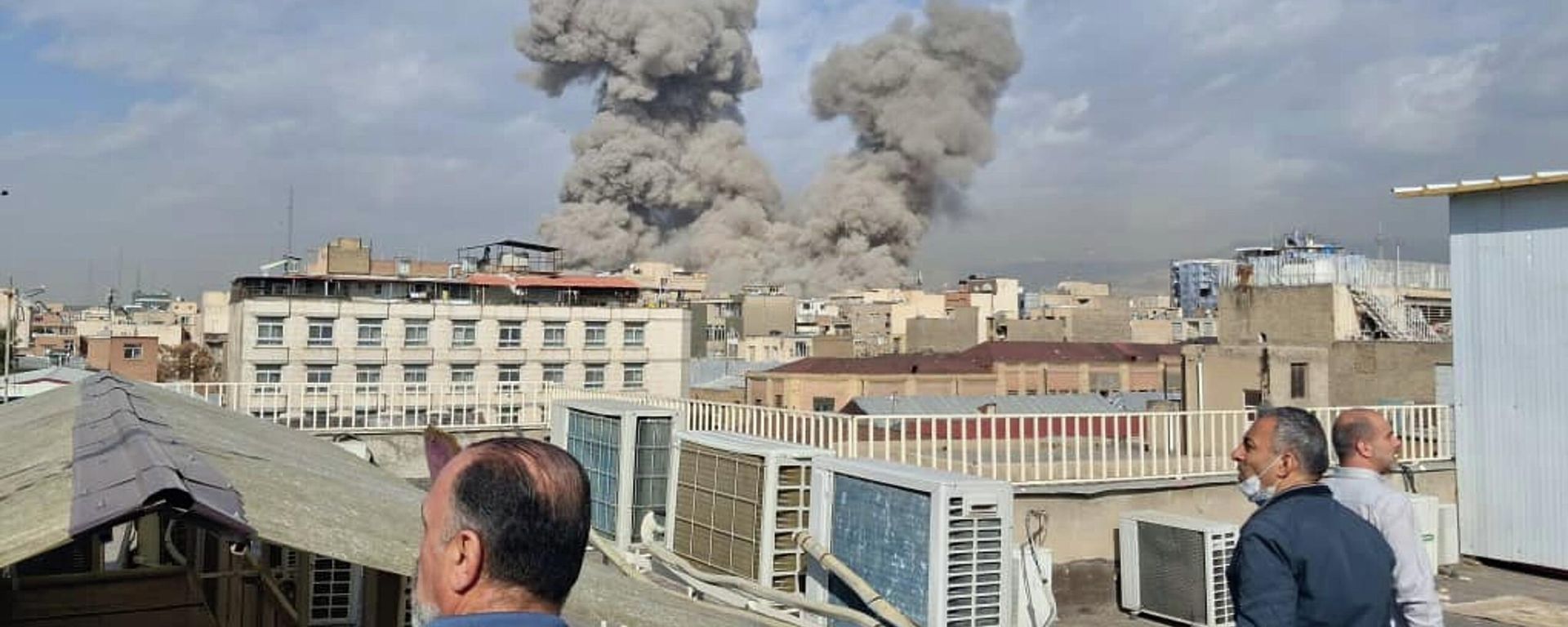 People watch as smoke rises on the skyline after an explosion in Tehran, Iran, Saturday, Feb. 28, 2026.(AP Photo) - Sputnik International, 1920, 28.02.2026