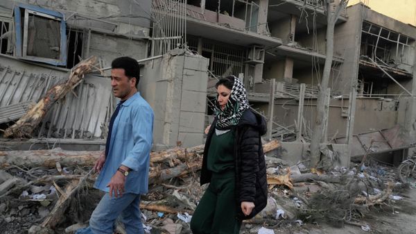 People walk past buildings damaged during a strike on a police station during ongoing, joint U.S.-Israeli military attacks in Tehran, Iran, Monday, March 2, 2026. - Sputnik International