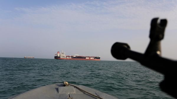In this Sunday, July 21, 2019 photo, a speedboat of Iran's Revolutionary Guard trains a weapon toward the British-flagged oil tanker Stena Impero, which was seized in the Strait of Hormuz on Friday by the Guard, in the Iranian port of Bandar Abbas. Global stock markets were subdued Monday while the price of oil climbed as tensions in the Persian Gulf escalated after Iran's seizure of a British oil tanker on Friday.  - Sputnik International