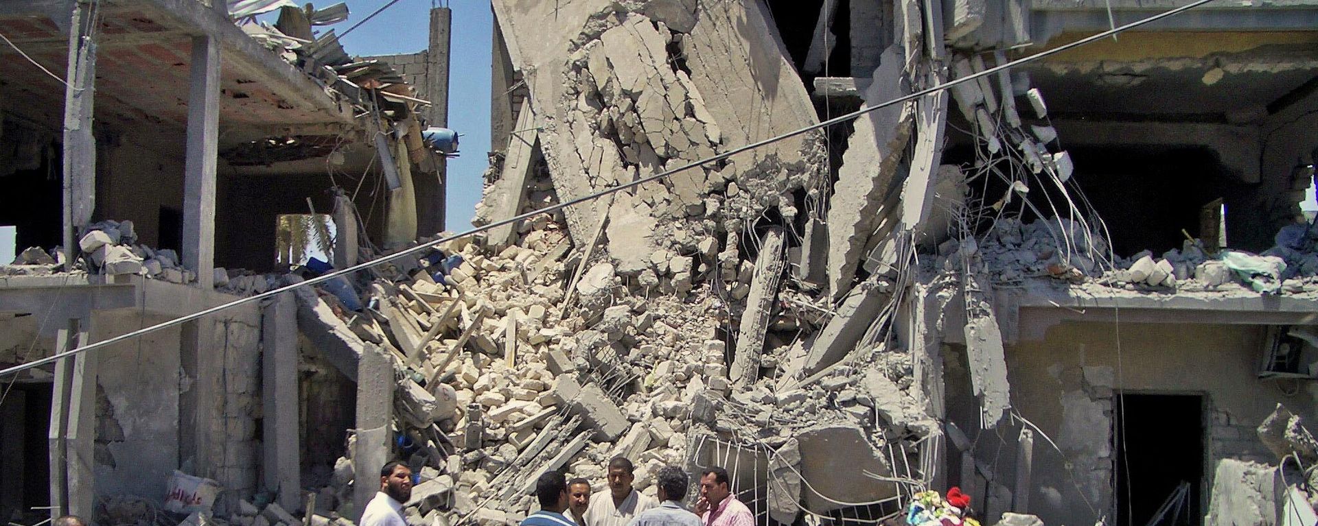 In a June 19, 2011, file photo made on a government-organized tour, members of the media and others examine the remains of a damaged residential building in Tripoli, Libya. - Sputnik International, 1920, 19.03.2026