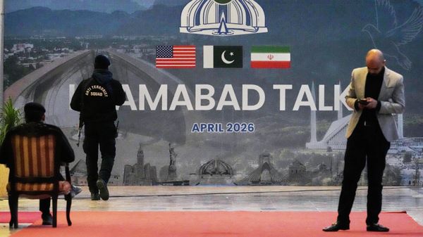 A security guard walks past a billboard  of the U.S. Iran talks outside a media center set up for the coverage of the US-Iran official meeting, in Islamabad, Pakistan, April 12, 2026.  - Sputnik International