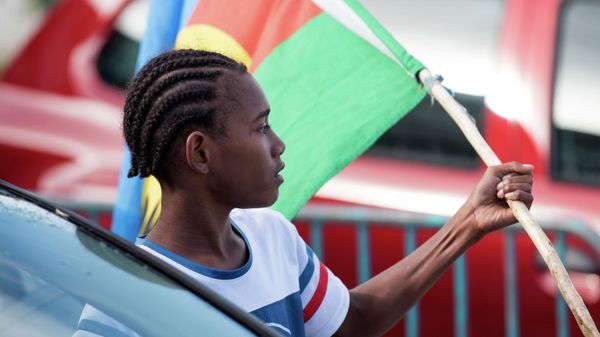 An Independence supporter holds the Kanak flag outside a voting station in the Riviere Salee district of Noumea, New Caledonia, Oct.4, 2020. - Sputnik International