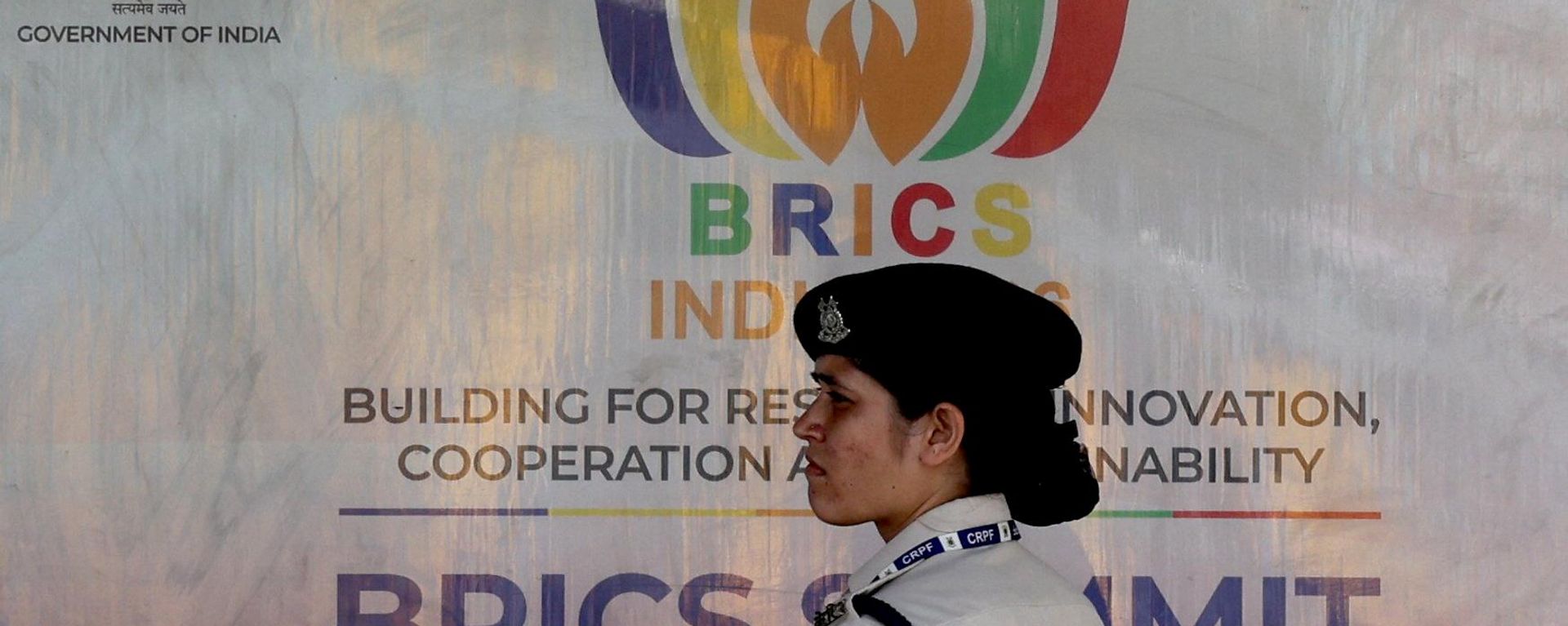A member of the Central Reserve Police Force (CRPF) stands in front of a hoarding displayed near Bharat Mandapam, the venue of the upcoming BRICS Summit in New Delhi, India - Sputnik International, 1920, 11.09.2026