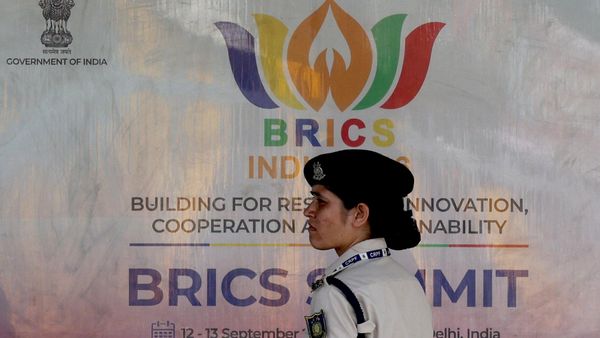 A member of the Central Reserve Police Force (CRPF) stands in front of a hoarding displayed near Bharat Mandapam, the venue of the upcoming BRICS Summit in New Delhi, India - Sputnik International