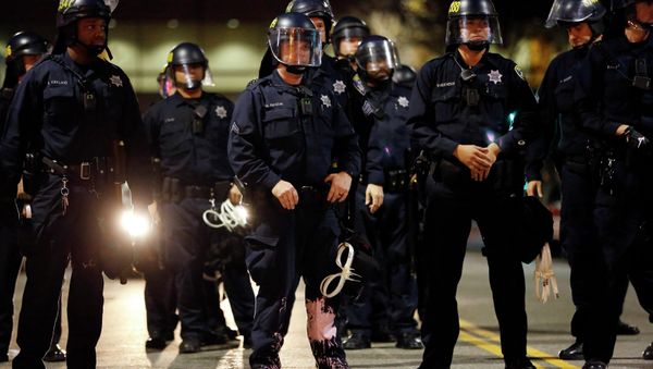A police officer looks into the crowd, after he was hit on the leg with paint thrown by protesters during an evening demonstration against police violence, in Oakland, California December 13, 2014 A police officer looks into the crowd, after he was hit on the leg with paint thrown by protesters during an evening demonstration against police violence, in Oakland, California December 13, 2014 - Sputnik International