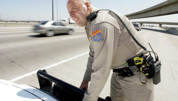 An Arizona Department of Public Safety officer adjusts the infrared license plate scanner mounted on the front bumper of his police cruiser along the I-10 in Phoenix. - Sputnik International