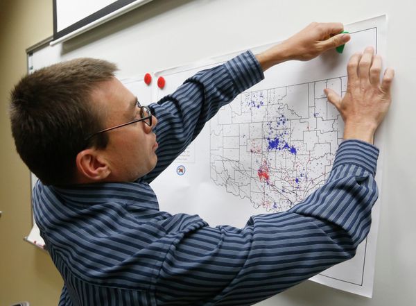 Austin Holland, research seismologist at the Oklahoma Geological Survey, hangs up a chart depicting earthquake activity. - Sputnik International