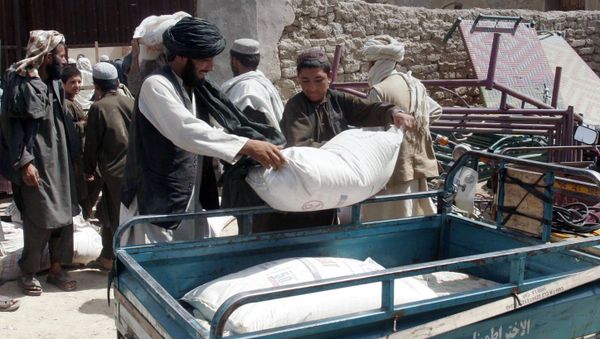 Afghans put a sack of wheat on the carrier back of a motor bike during a food distribution to displaced families from Helmand province. Afghans put a sack of wheat on the carrier back of a motor bike during a food distribution to displaced families from Helmand province. - Sputnik International
