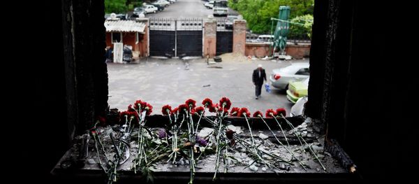 Flowers on a broken window in memory of the people killed by fire in the Trade Unions House on Odessa's Kulikovo Field Square. - Sputnik International
