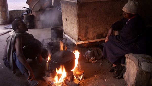 Homeless squatters sit near a fire to keep away the cold early in the morning in Johannesburg Homeless squatters sit near a fire to keep away the cold early in the morning in Johannesburg - Sputnik International