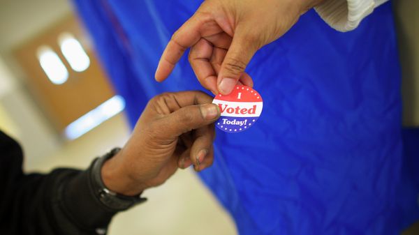 Voting machine operator Robin Coffee-Ruff hands a sticker to a voter who cast his ballot at West Philadelphia High School on U.S. midterm election day morning in Philadelphia, Pennsylvania, November 4, 201 - Sputnik International