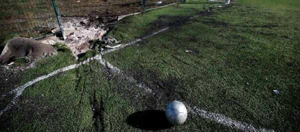 A ball is seen near a crater caused by shelling at a school's soccer field in Donetsk, eastern Ukraine. - Sputnik International