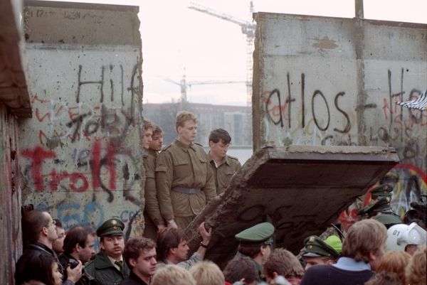 East German border guards look through a hole in the Berlin wall after demonstrators pulled down one segment of the wall at Brandenburg gate Saturday, November 11, 1989. - Sputnik International