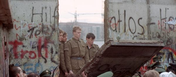 East German border guards look through a hole in the Berlin wall after demonstrators pulled down one segment of the wall at Brandenburg gate Saturday, November 11, 1989. - Sputnik International