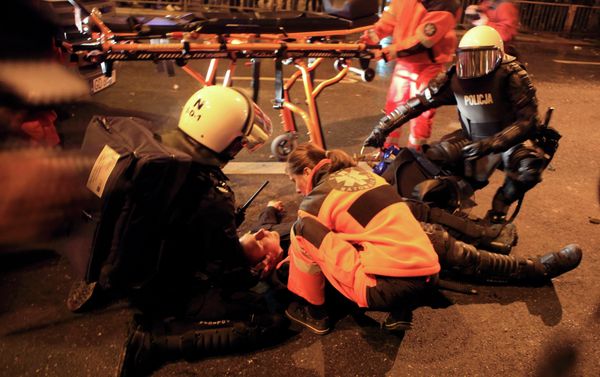 A wounded riot policeman is attended after several hundred masked men broke away from a far-right march and threw stones and flares in Warsaw November 11, 2014 - Sputnik International