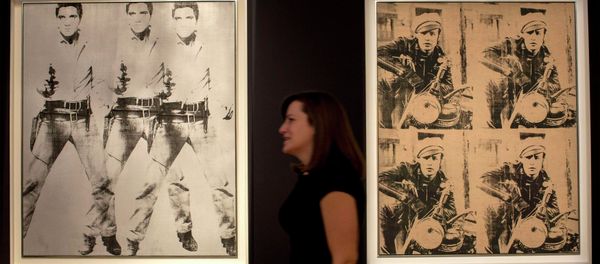 A woman walks between Triple Elvis and Four Marlons by Andy Warhol during a media preview at Christie's auction house in New York - Sputnik International