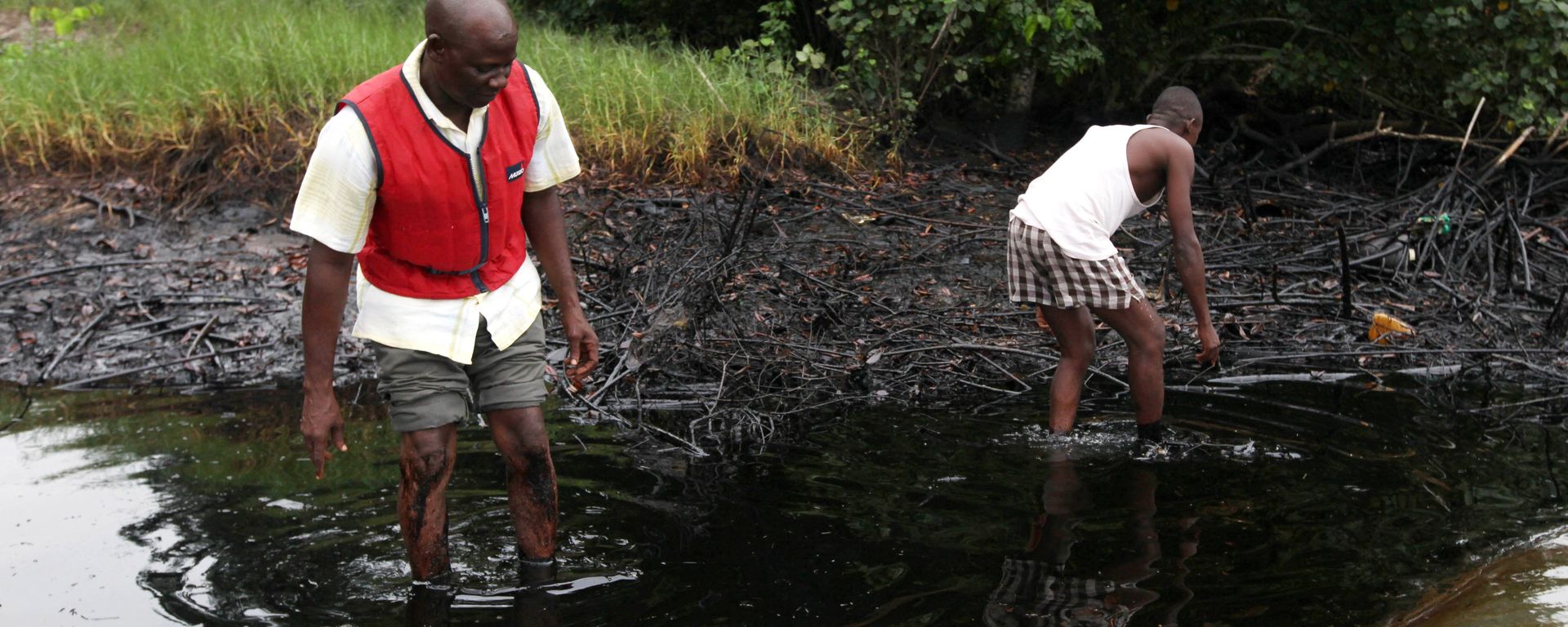 In this June 20, 2010 file photo, men walk in an oil slick covering a creek near Bodo City in the oil-rich Niger Delta region of Nigeria - Sputnik International, 1920, 05.10.2022