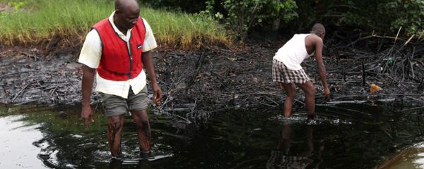 In this June 20, 2010 file photo, men walk in an oil slick covering a creek near Bodo City in the oil-rich Niger Delta region of Nigeria - Sputnik International