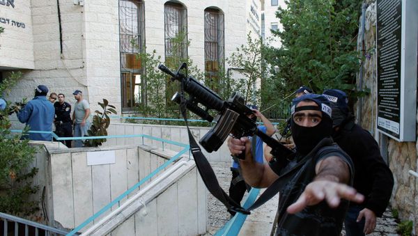 An Israeli police officer gestures as he holds a weapon near the scene of an attack at a Jerusalem synagogue. - Sputnik International