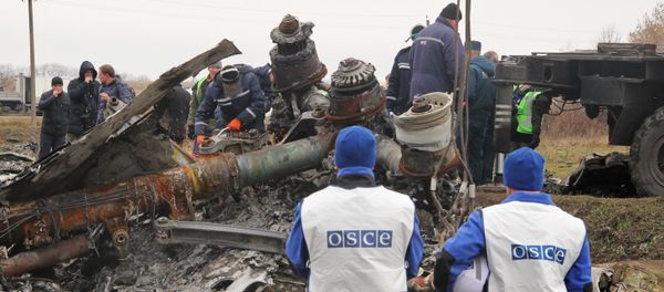 Members of a crew of the Donetsk People's Republic's Emergencies Ministry attempt to saw a gear leg of the Malaysia Airlines Boeing 777 - Sputnik International