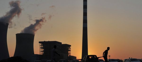 A worker pulls a cart in front of the smoking chimneys of a power plant in Hefei A worker pulls a cart in front of the smoking chimneys of a power plant in Hefei - Sputnik International