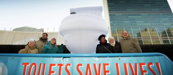 A small group of UN staff, with a “Toilets Save Lives!” banner, poses for a photo with a 15-foor-high inflatable toilet, in front of United Nations headquarters - Sputnik International