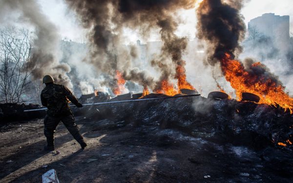A radical opposition member rolls tires into flames on Institutskaya Street, Kiev. A radical opposition member rolls tires into flames on Institutskaya Street, Kiev. - Sputnik International