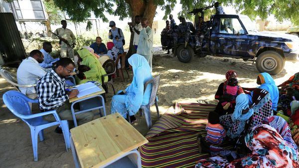 Special Prosecutor for Crimes in Darfur Yasir Ahmed Mohamed (back, in blue shirt with glasses) and his team talk to women during an investigation into allegations of mass rape in the village of Tabit Special Prosecutor for Crimes in Darfur Yasir Ahmed Mohamed (back, in blue shirt with glasses) and his team talk to women during an investigation into allegations of mass rape in the village of Tabit - Sputnik International