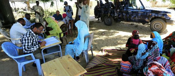 Special Prosecutor for Crimes in Darfur Yasir Ahmed Mohamed (back, in blue shirt with glasses) and his team talk to women during an investigation into allegations of mass rape in the village of Tabit - Sputnik International